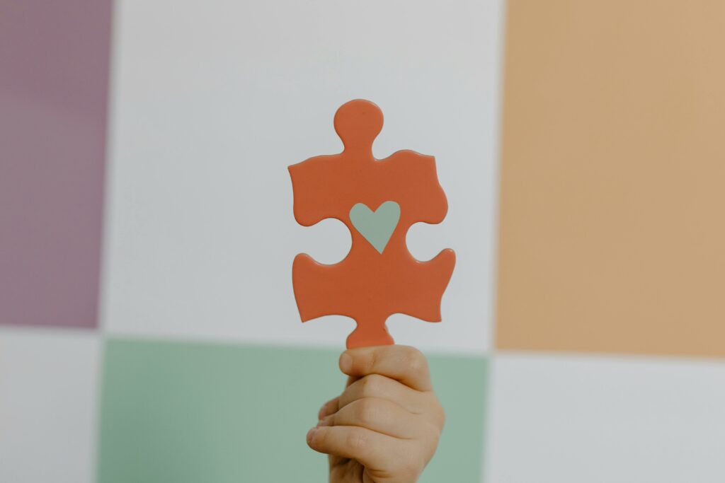 S'informer - Se former A hand holds a red puzzle piece with a heart, symbolizing connection and awareness.