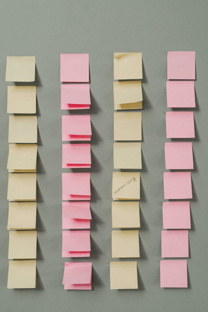 Vertical arrangement of pink and yellow sticky notes on a gray background.